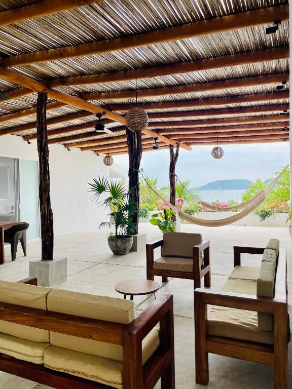 a living room with a couch and chairs and a hammock at Casa A la Mar in Zihuatanejo