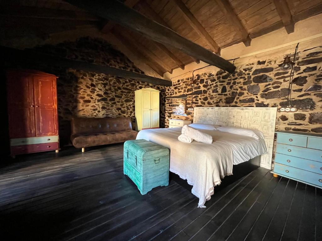 a bedroom with a bed and a stone wall at La Casina de Gelo in Riego de Ambros