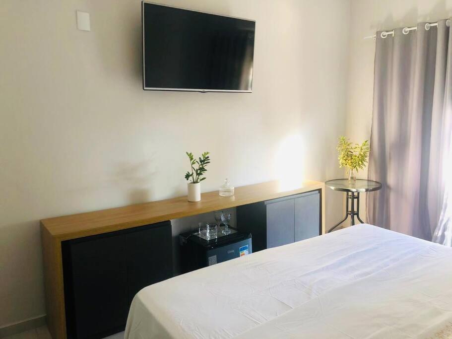 a bedroom with a bed and a tv on the wall at Suíte confortável no centro in Delfinópolis