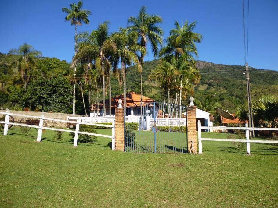una recinzione bianca in un campo con palme di Casa Coronel Estevão a Santo Antônio do Jardim