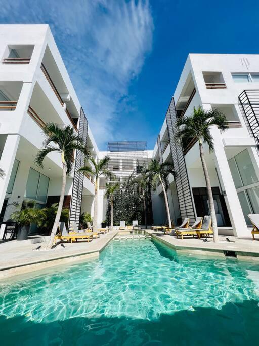 a swimming pool in front of a building with palm trees at Elegant Coastal Studio in Bucerías