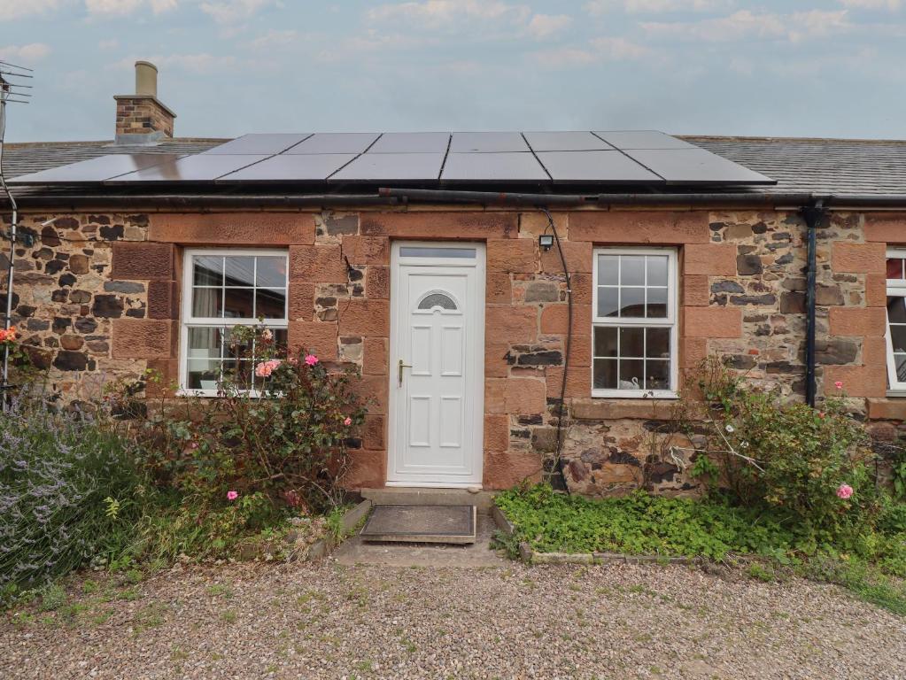 a brick house with solar panels on the roof at Budle Bay Cottage in Bamburgh