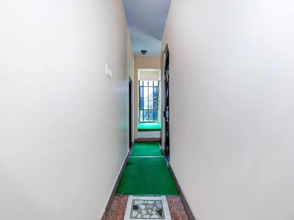 a corridor with a green floor in a building at Hotel O Flagship Adhya Inn in Nainital