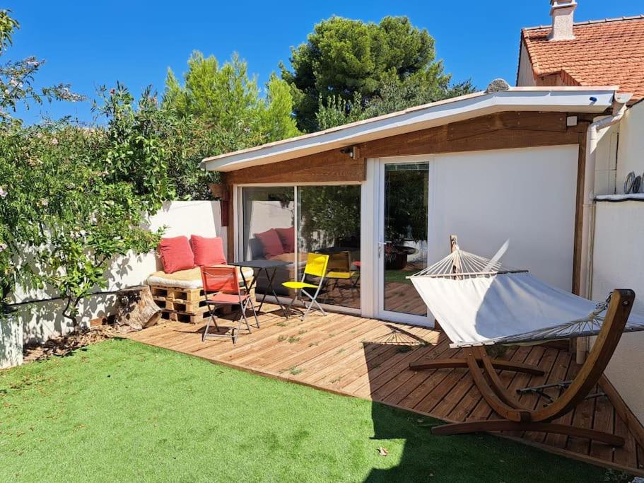 - une terrasse en bois avec un hamac et des chaises dans la cour dans l'établissement Les Bruyères, à Marseille