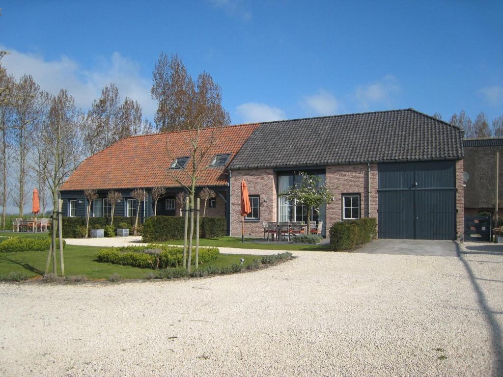 a brick house with a black garage at Rural holiday home with outdoor pool & sauna in Zuidzande