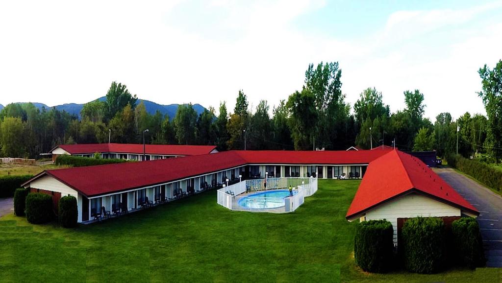 a large building with a swimming pool in the grass at Hotel Motel Bonsoir in Granby