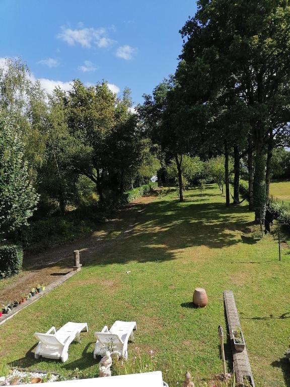 un parc avec deux tables de pique-nique blanches et un banc dans l'établissement Chambre d'hôtes Ste Marie, à Sainte-Marie