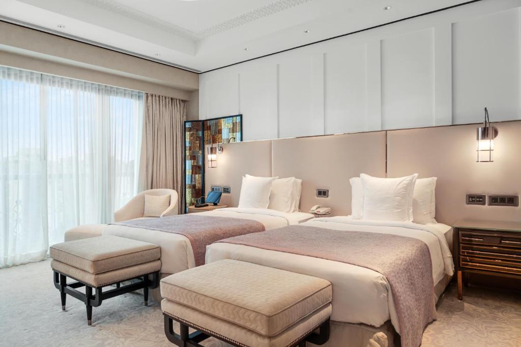 a hotel room with two beds and a chair at ITC Narmada, a Luxury Collection Hotel, Ahmedabad in Ahmedabad