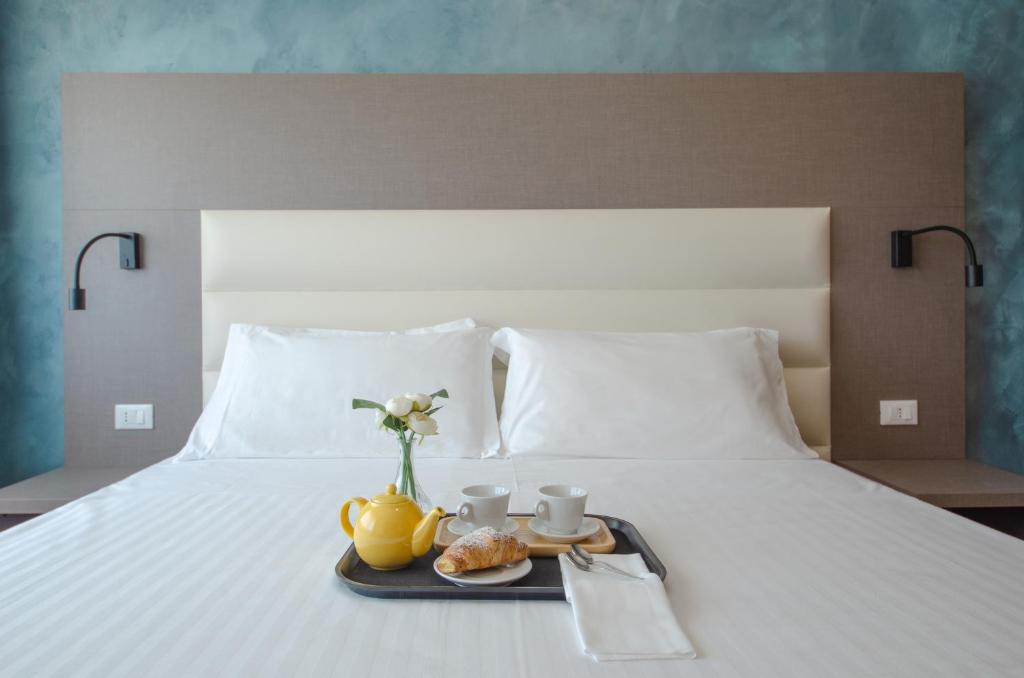 a tray with two cups and a vase with flowers on a bed at Hotel Palace del Conero in Osimo