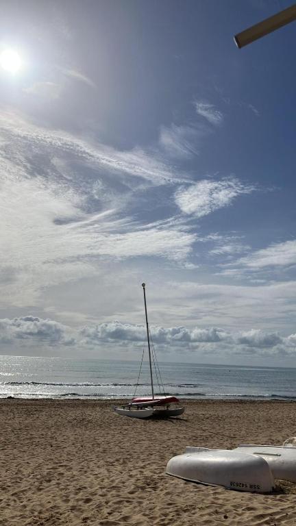 a boat on the beach with a surfboard on the sand at Tus vacaciones junto al mar in Torrevieja