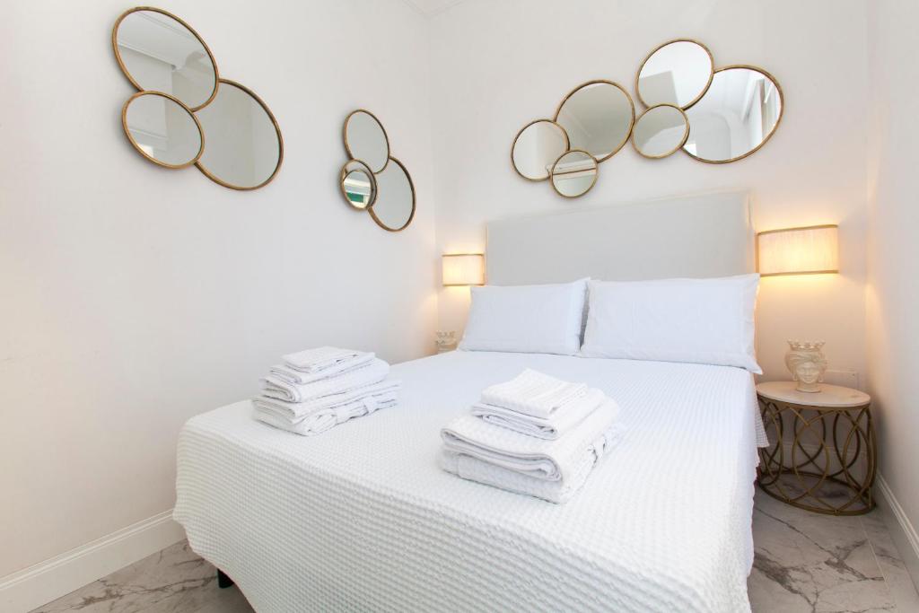 una camera da letto con un letto bianco e specchi sul muro di La Finestra Sul Mare Central Apartment Vista mare ad Anzio