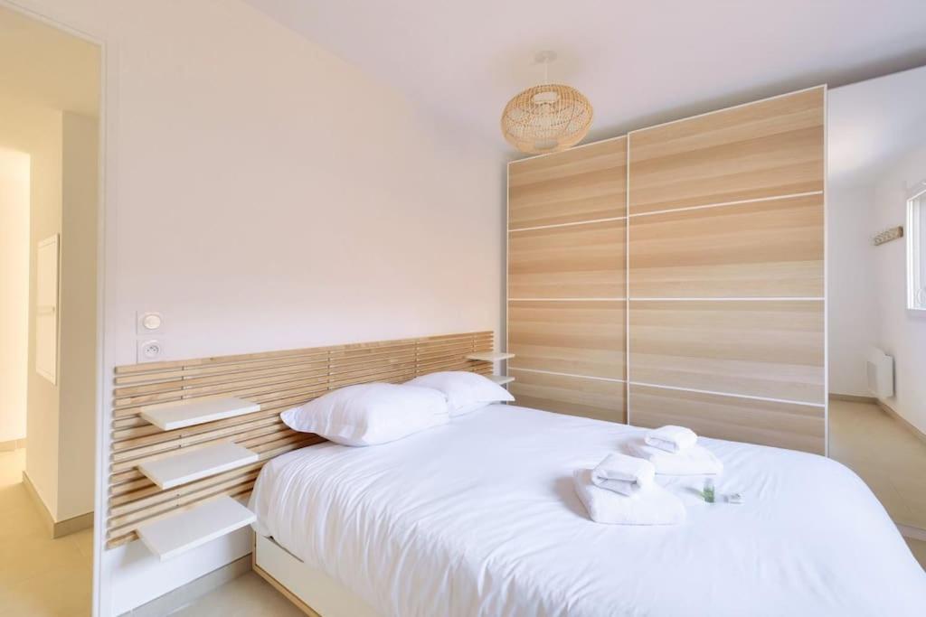 - une chambre avec un grand lit blanc et une tête de lit en bois dans l'établissement T2 avec Terrasse et Parking privé au coeur de Nice, à Nice