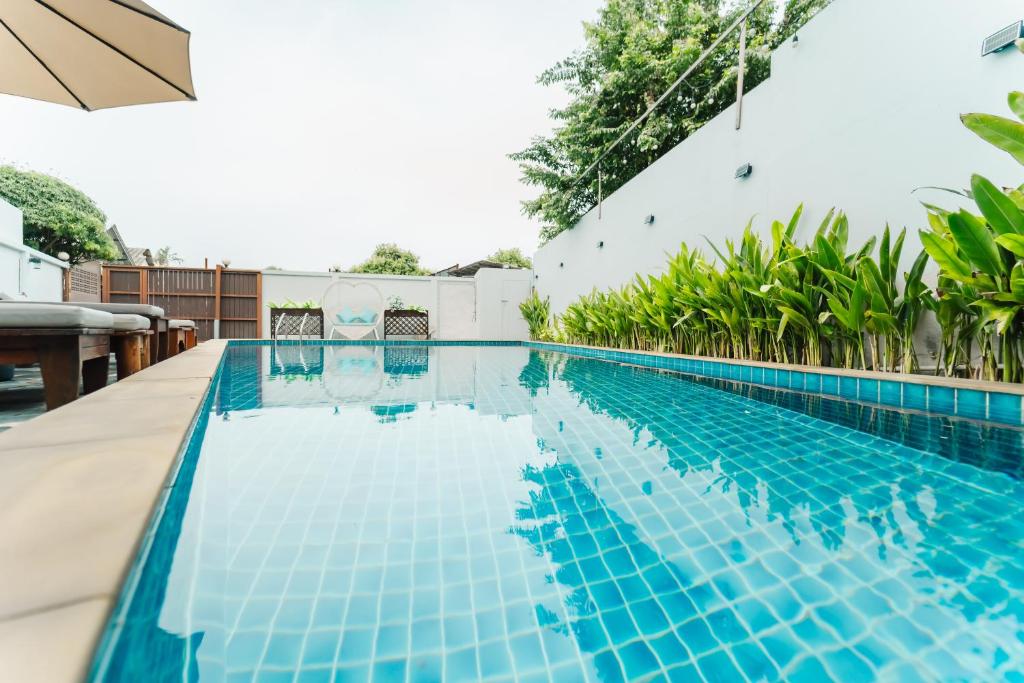 a blue swimming pool with trees in the background at Saiyuan Residence Phuket in Rawai Beach