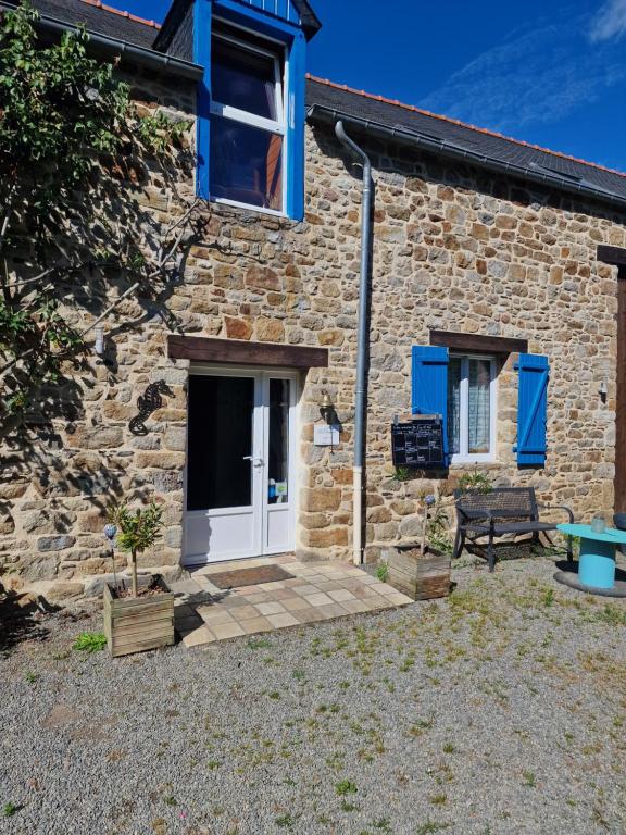 Ce cottage en pierre dispose de fenêtres bleues et d'une porte blanche. dans l'établissement LES CHEVAUX DE L'HIPPOCAMPE, à Mont-Dol