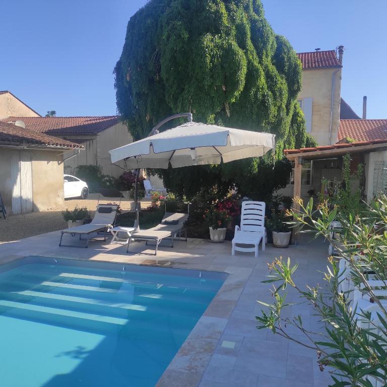une piscine avec des chaises et un parasol dans l'établissement L'Acacia, à Bergerac