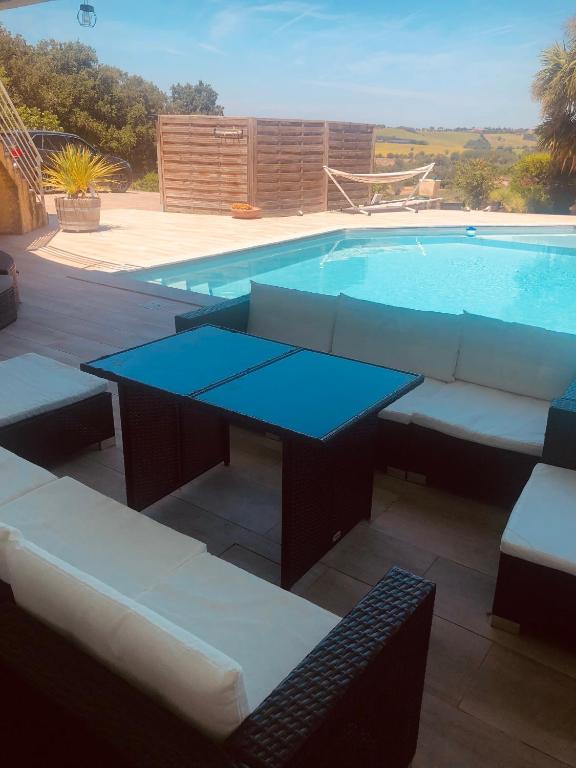 - une table et des canapés à côté de la piscine dans l'établissement T2 de 50m2 indépendant à 15mn de Toulouse, à Préserville