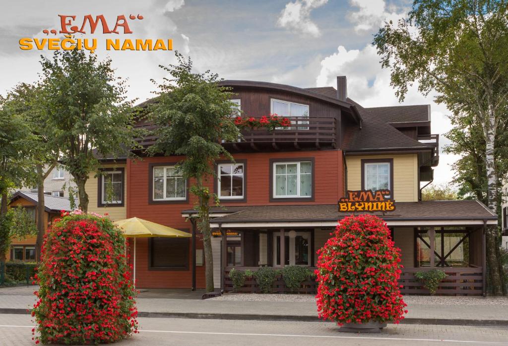 un edificio con dos grandes flores rojas delante de él en Ema, en Palanga