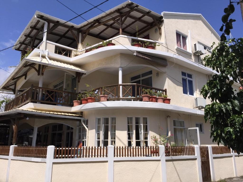 a large white building with potted plants on it at Studio Manguillier in Trou d'Eau Douce