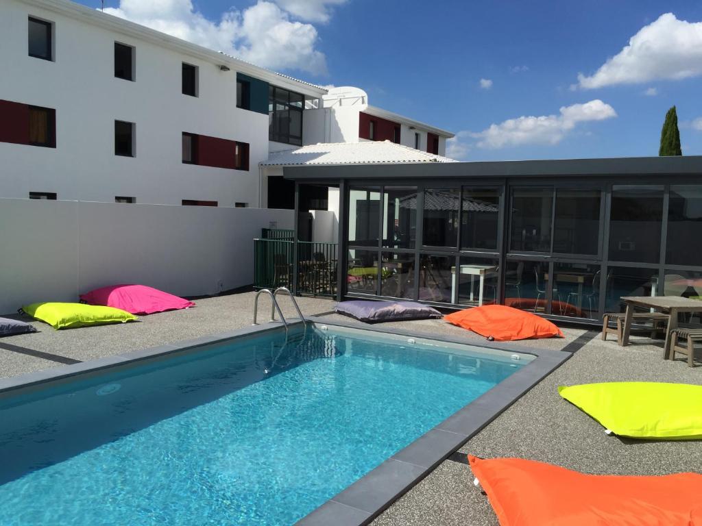 une piscine devant un immeuble dans l'établissement Kyriad Direct La Rochelle Aytré, à Aytré