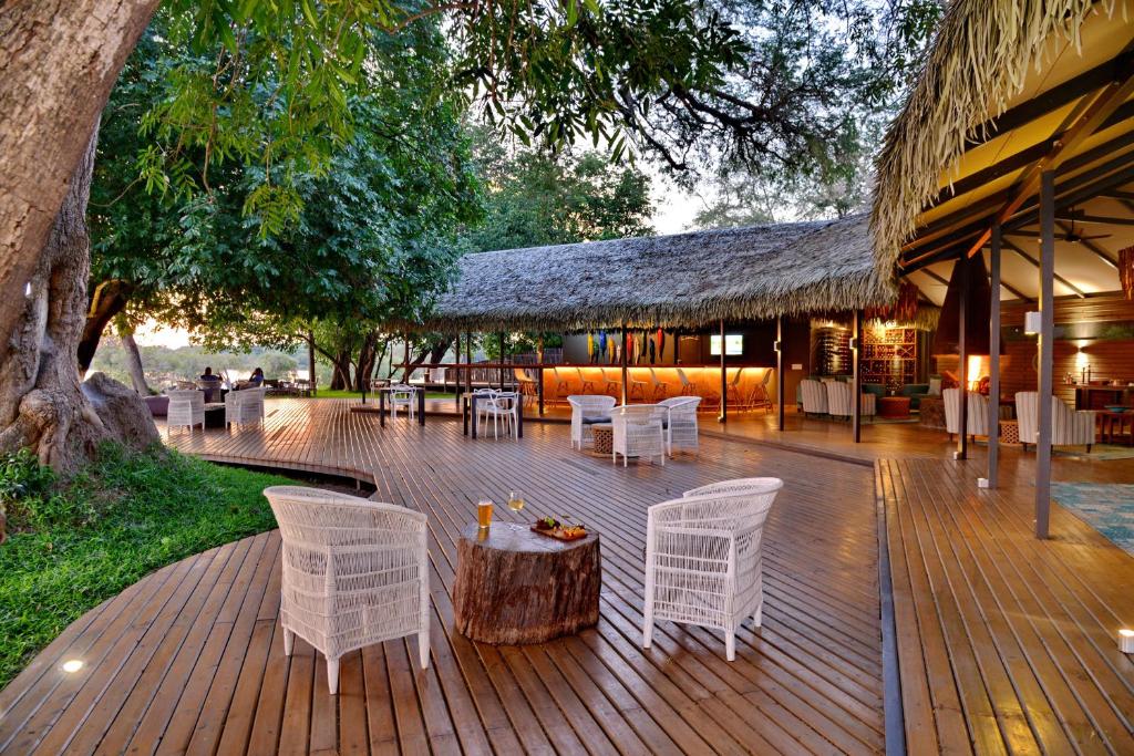 a deck with white chairs and a table and a building at Chundu Island in Victoria Falls