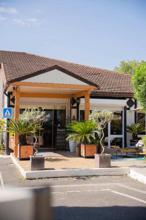 een gebouw met potplanten ervoor bij Kyriad Nîmes Ouest A9 in Nîmes