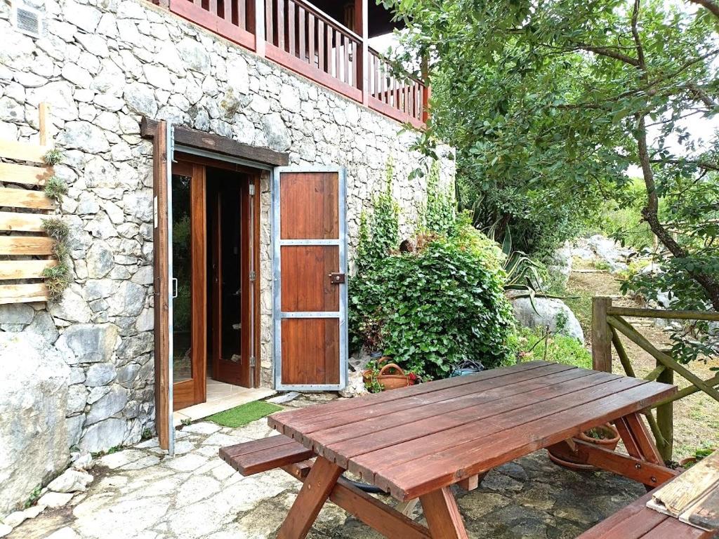 a wooden picnic table in front of a stone building at Quinta do Castelo, Casa de Campo de Pedra in Reguengo Grande