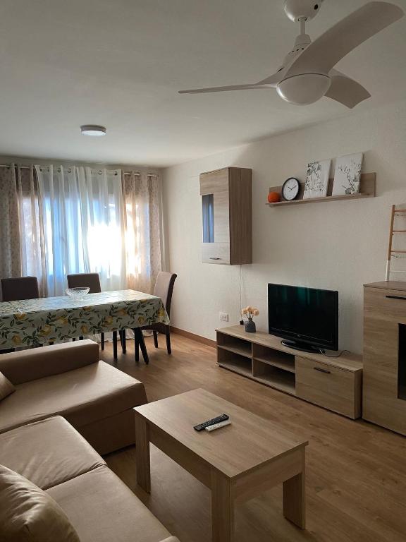 a living room with a couch and a tv and a table at La Cañada in Candeleda