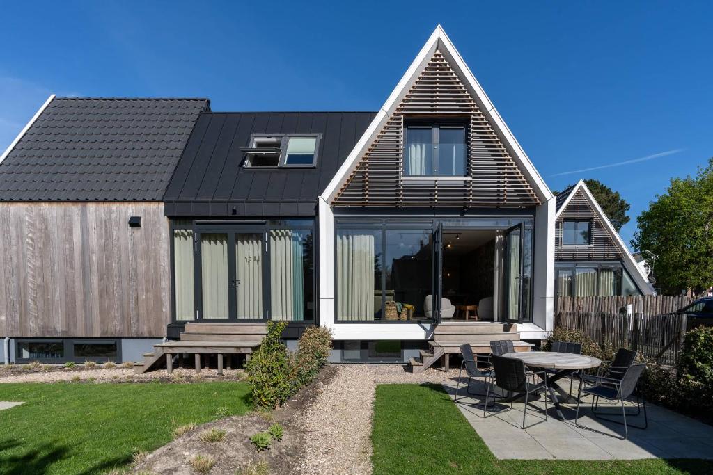 a house with a black roof and a table and chairs at Hello Zeeland - Appartement Duno Lodge I in Oostkapelle