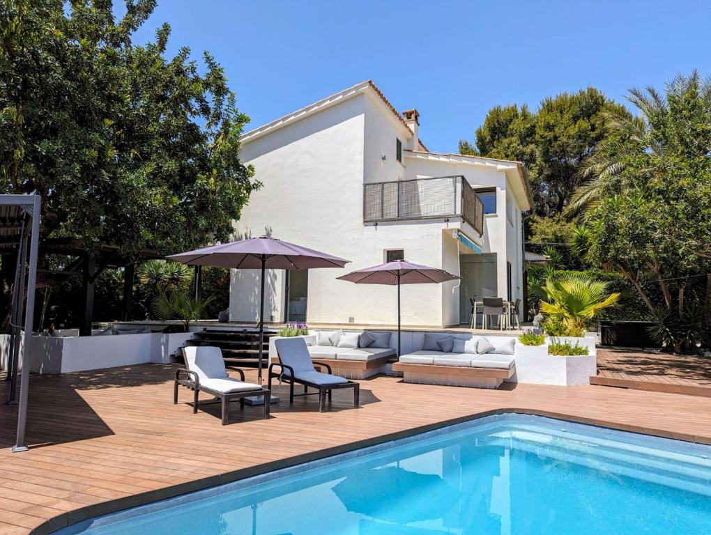 a swimming pool with chairs and umbrellas next to a house at Casa Guindilla in Portals Nous