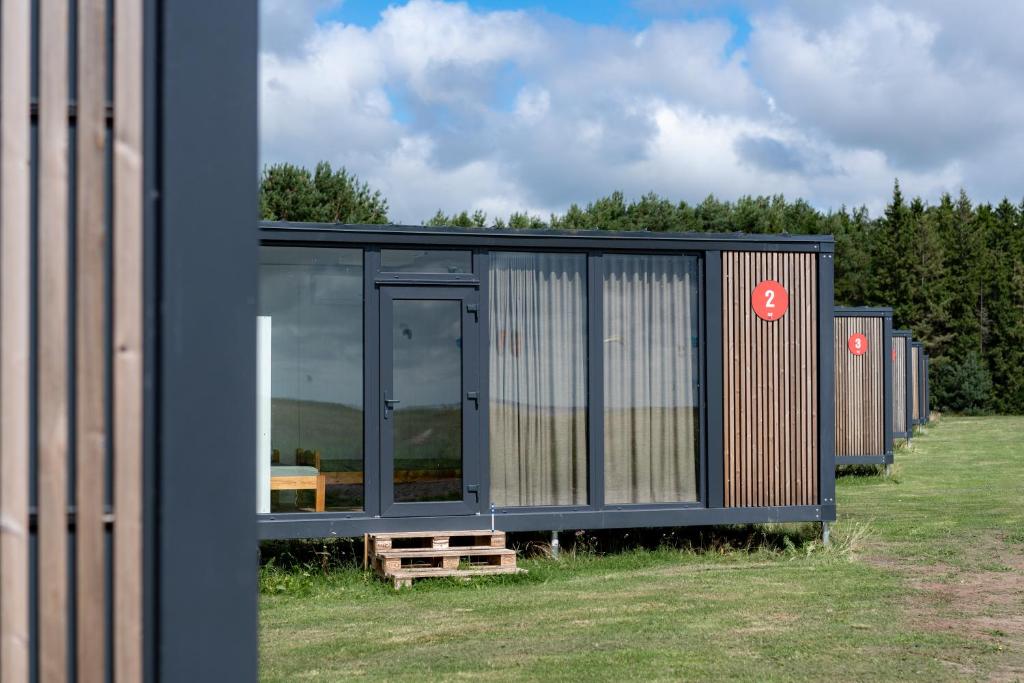 a black house with glass windows on a field at BoardHouse Spot in Svencelė