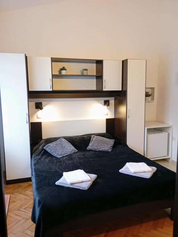a bedroom with a black bed with two pillows at Rooms Helena in Krk