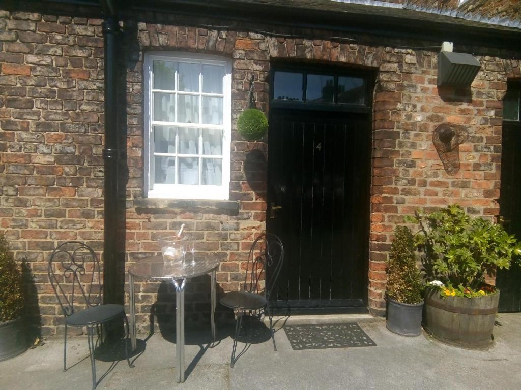 a table and chairs in front of a brick building with a black door at Masons Arms in York
