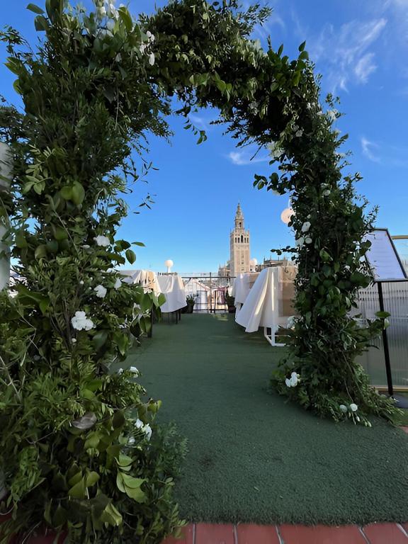 an arch with white tables and flowers on a roof at Hotel Convento La Gloria in Seville