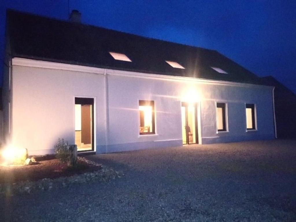 une maison blanche avec des lumières allumées la nuit dans l'établissement Fermette de charme rénovée avec grand terrain, 5 chambres, proche du circuit 24H du Mans - FR-1-410-304, à Savigné-lʼÉvêque