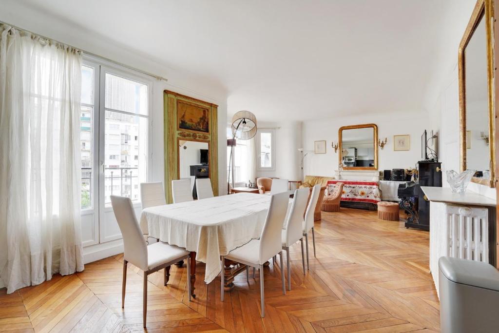 une salle à manger avec une table et des chaises blanches dans l'établissement 4 chambres 120m2 - Vue Tour Eiffel a Saint-Germain, à Paris