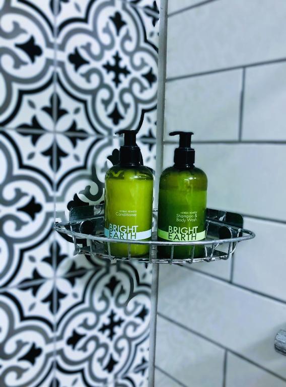 two green bottles on a shelf in a bathroom at The Vines Hotel in Alvescot