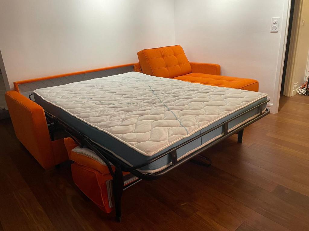 a bed in a room with an orange chair at Panoramique vue NEW design proche Tour Eiffel in Paris