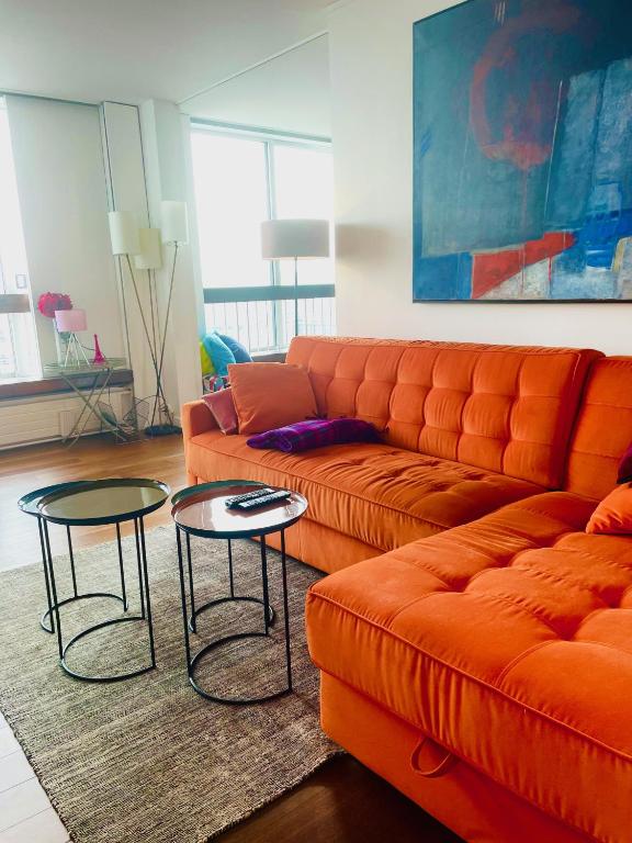 a living room with an orange couch and two tables at Panoramique vue NEW design proche Tour Eiffel in Paris