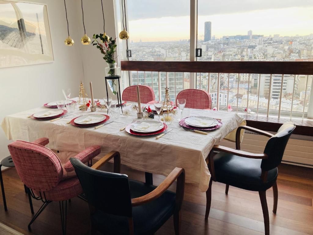 a dining room table with chairs and a large window at Panoramique vue NEW design proche Tour Eiffel in Paris
