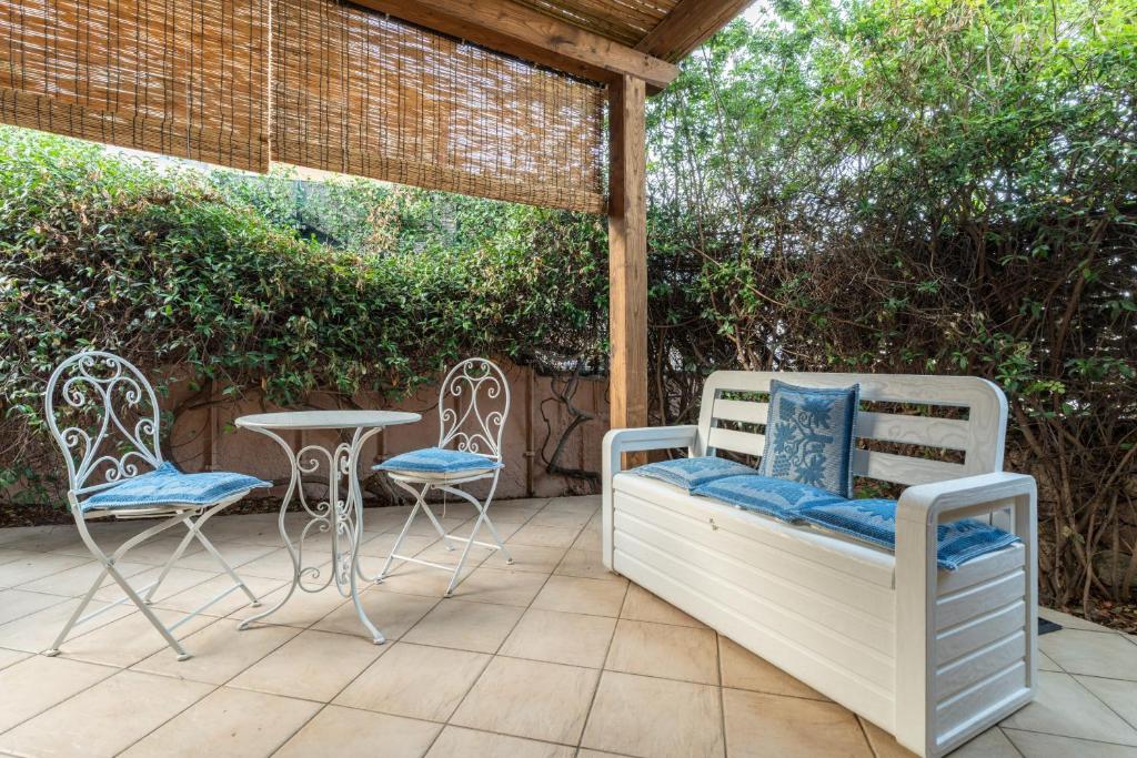 a patio with two chairs and a table and a bed and chairs at La Casetta di Lidia by Wonderful Italy in Cannigione