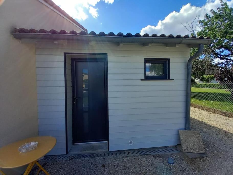 un petit hangar avec une porte noire et une table dans l'établissement Petit studio independant mitoyen à la maison, à Jaunay-Clan