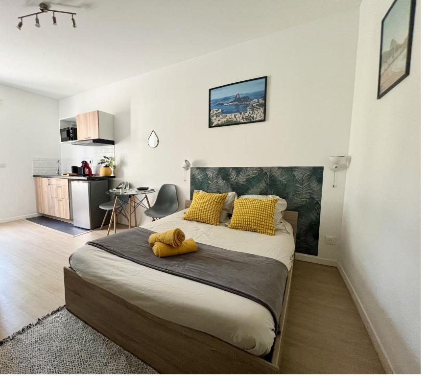 a bedroom with a large bed with yellow pillows at Studios modernes et chaleureux proche gare avec accès jardin in Châtellerault