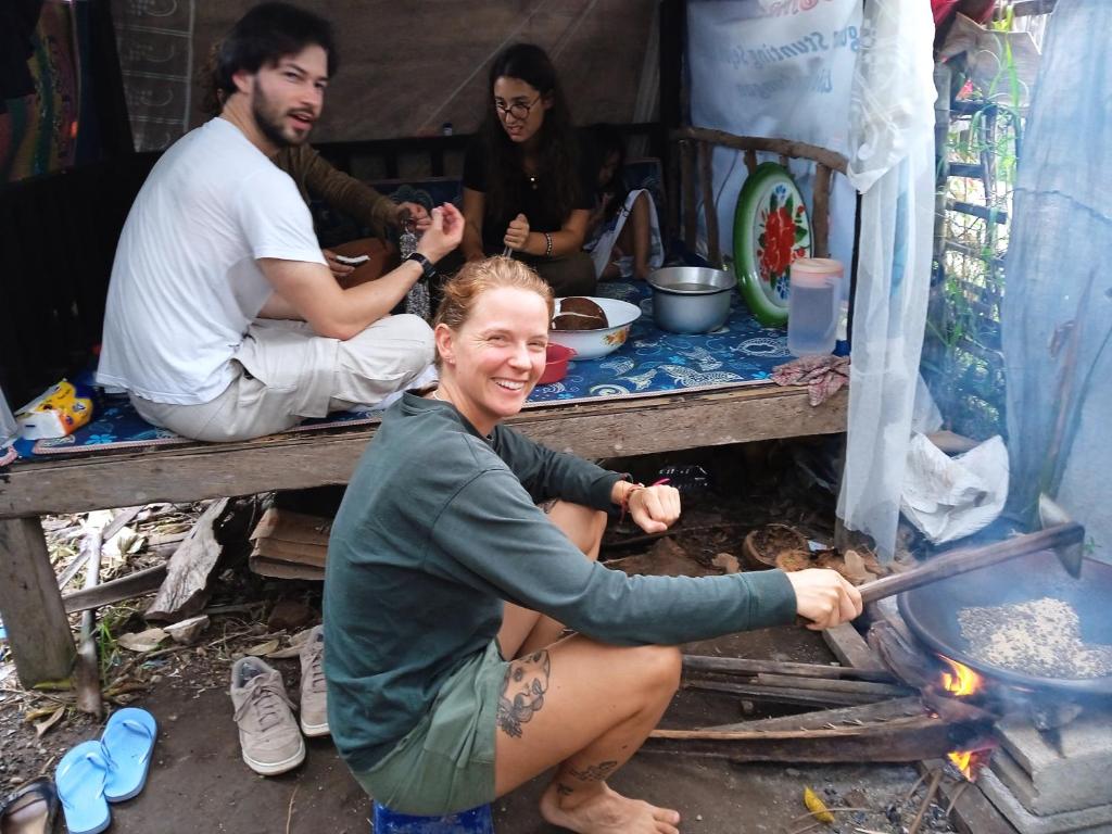 a woman sitting on a table with a stove at Citra Homestay in Tetebatu