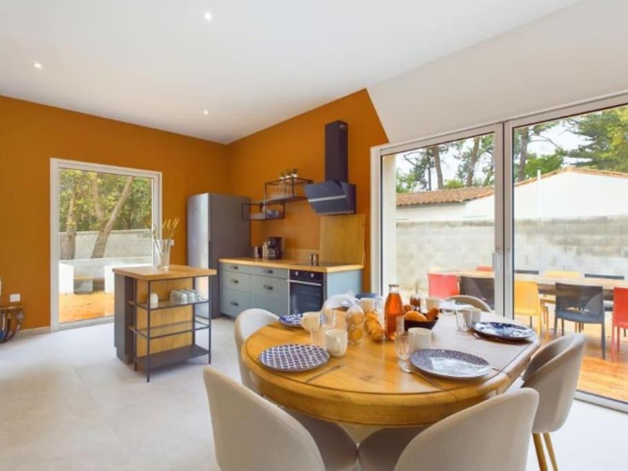 une cuisine et une salle à manger avec une table et des chaises en bois dans l'établissement Maison - 8 à 10 personnes les Grenettes, à Sainte-Marie de Ré