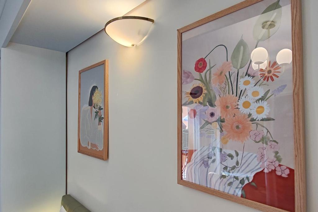 a painting of flowers on a wall with a light at Aparthotel AMMI Vieux Nice in Nice