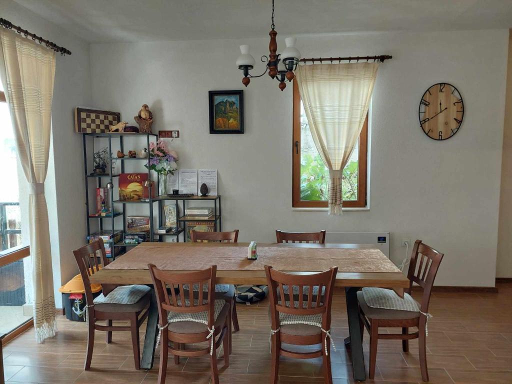 Un comedor con una mesa y sillas y un reloj. en Villa Victoria, en Stoykite