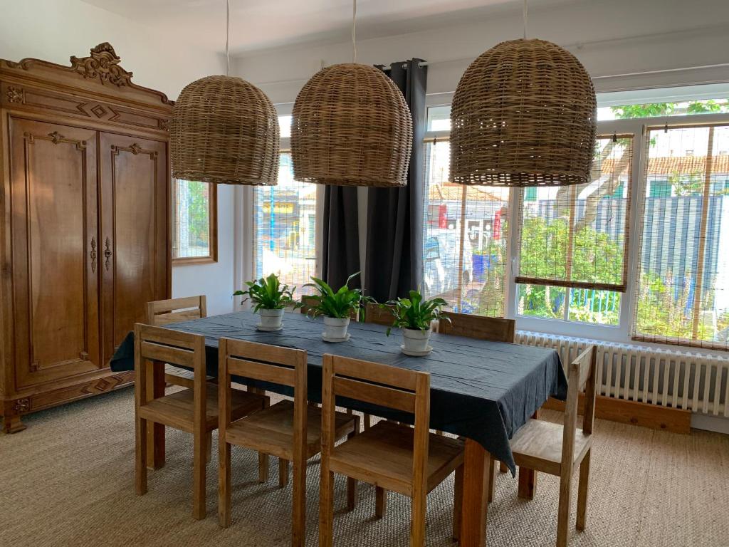 a dining room with a table and chairs and windows at La Désirade in Saint-Jean-de-Monts