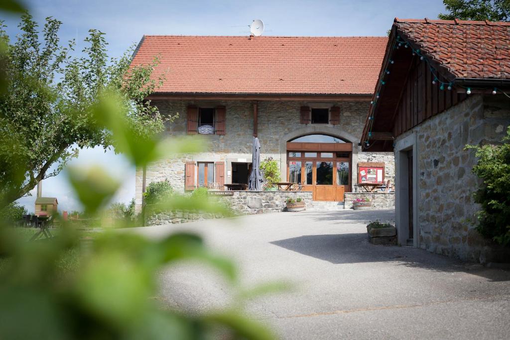 ein Steingebäude mit einem roten Dach und einer Garage in der Unterkunft Le Bonheur dans le Pré in Lucinges