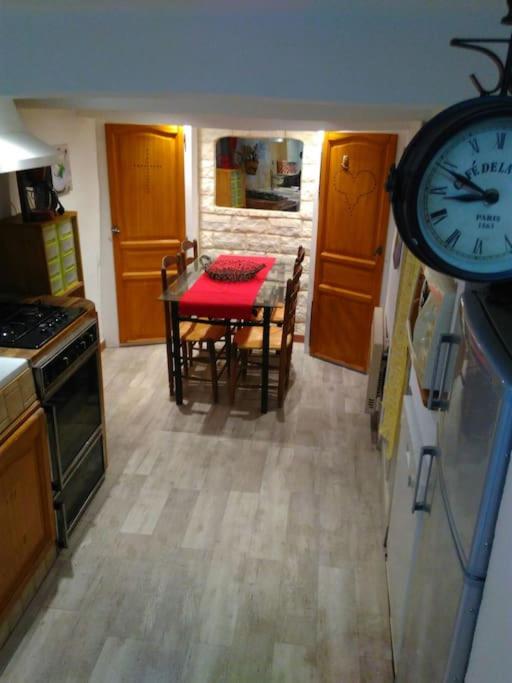 une cuisine avec une table et une horloge au mur dans l'établissement Coquette petite maison de village, à Aups