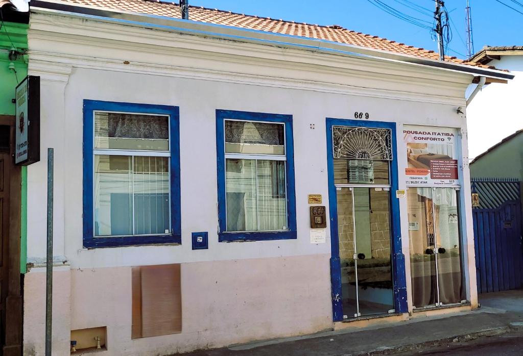 un antiguo edificio blanco con puertas y ventanas azules en Pousada Itatiba Conforto, en Itatiba